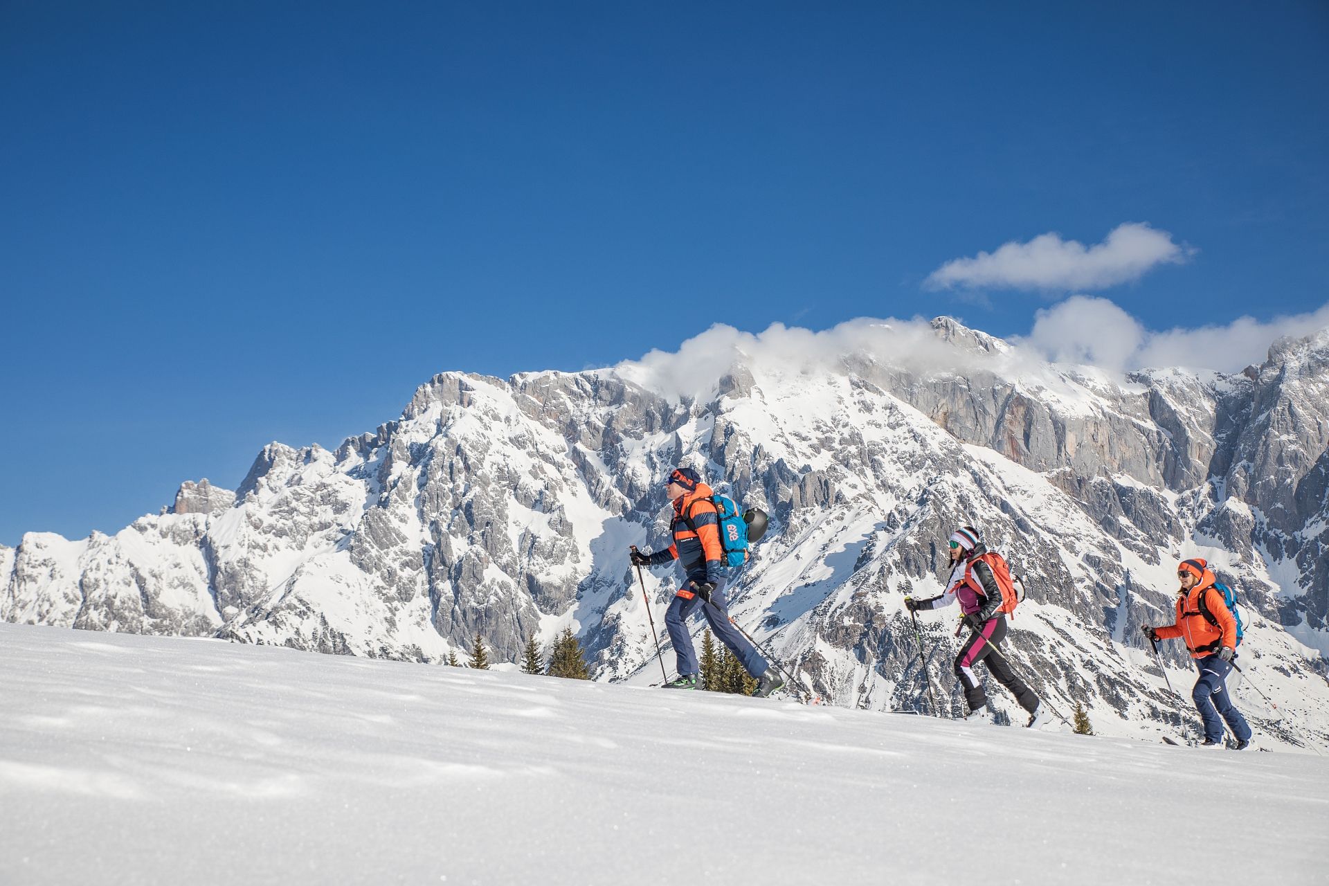 Drei Skitourengeher vor dem verschneiten Hochkönigmassiv