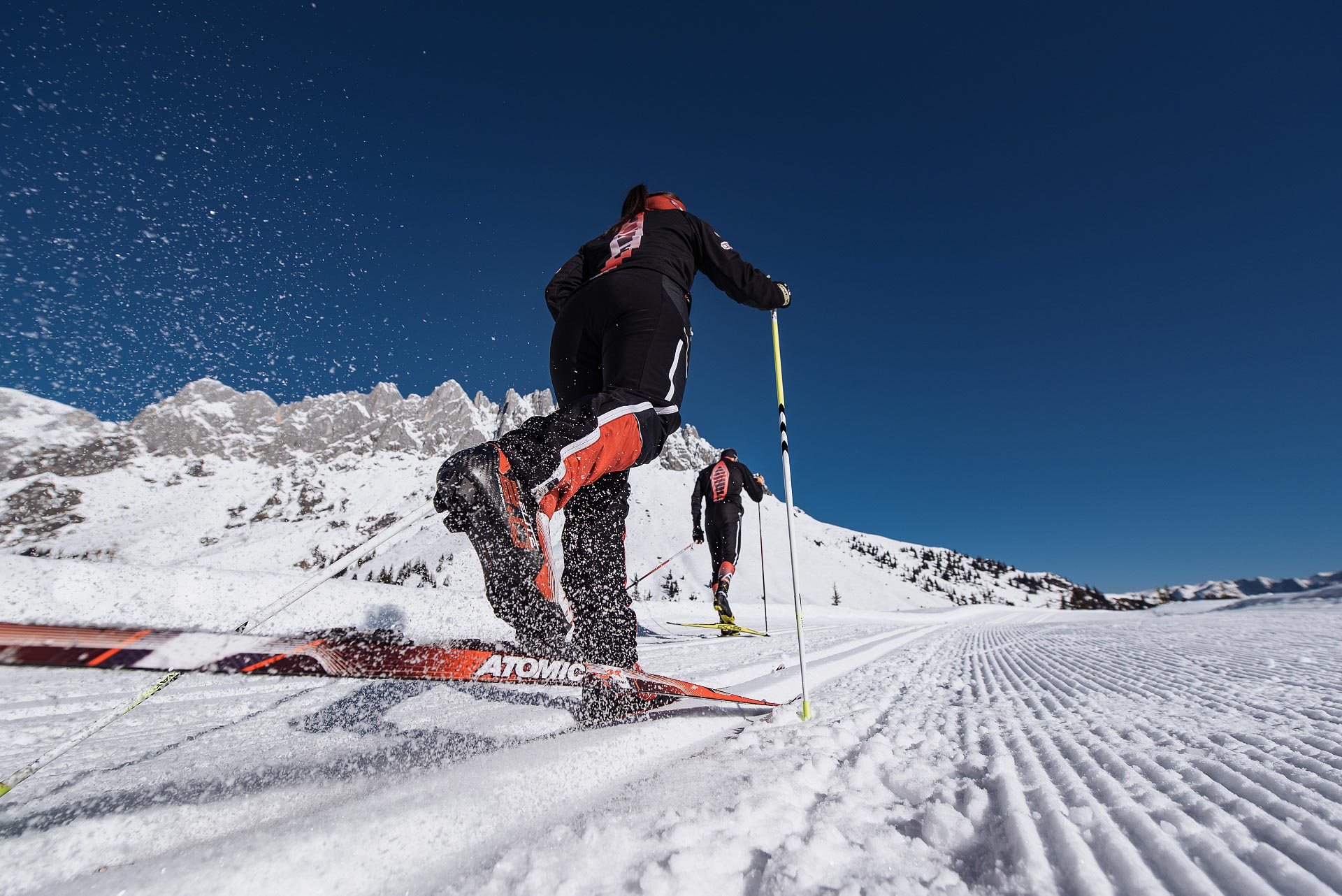 Zwei Langläufer auf einer Loipe vor dem verschneiten Hochkönigmassiv