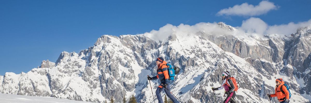 Drei Skitourengeher vor dem verschneiten Hochkönigmassiv
