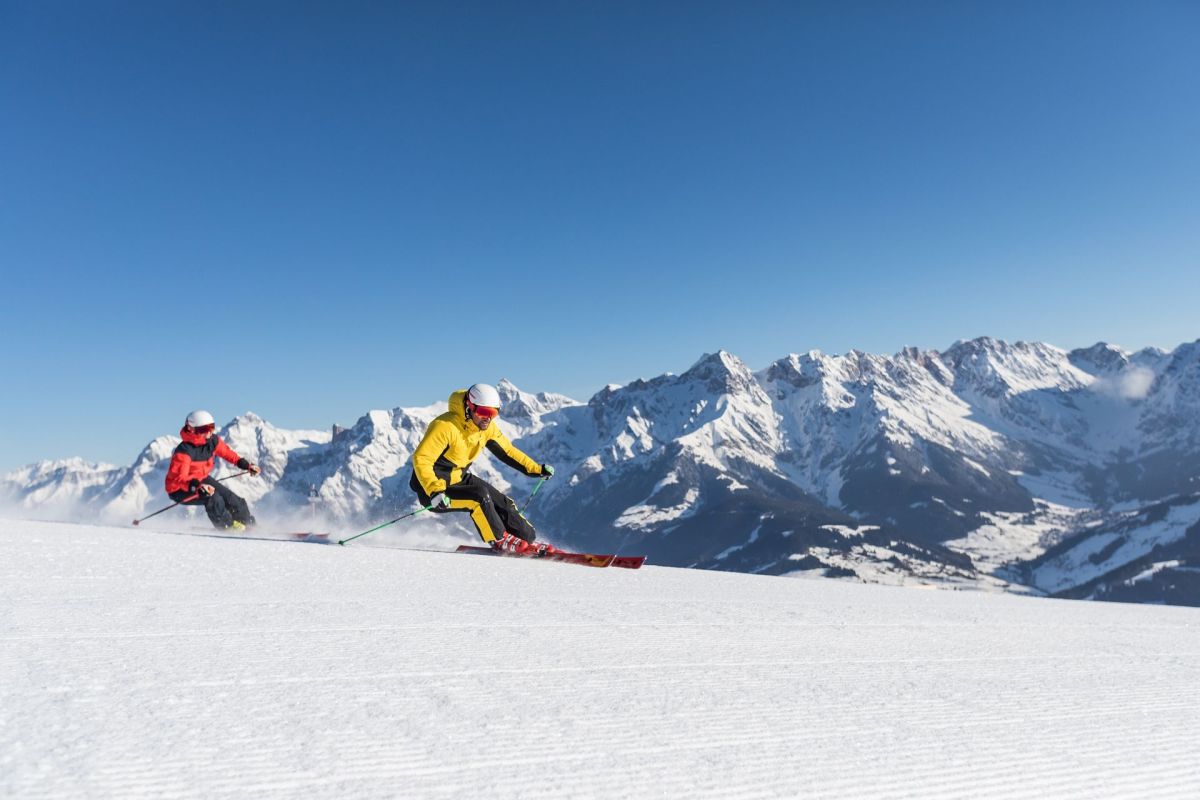 Zwei Skifahrer beim Carven vor dem Hochkönigmassiv