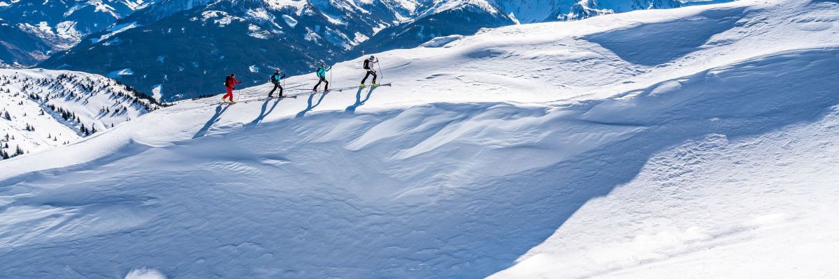 Vier Skitourengeher beim Aufstieg über einen verschneiten Berghang