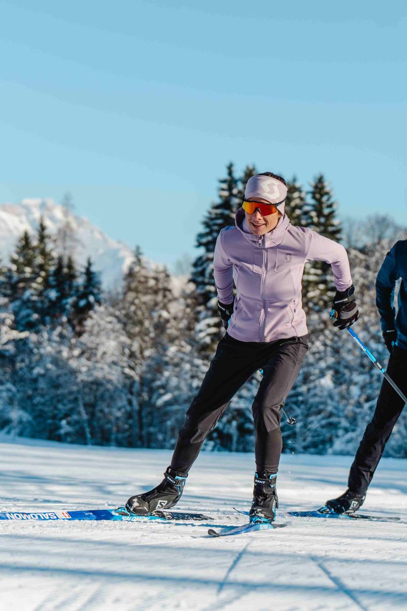 Langläuferin und Langläufer beim Skating in sonniger Winterlandschaft