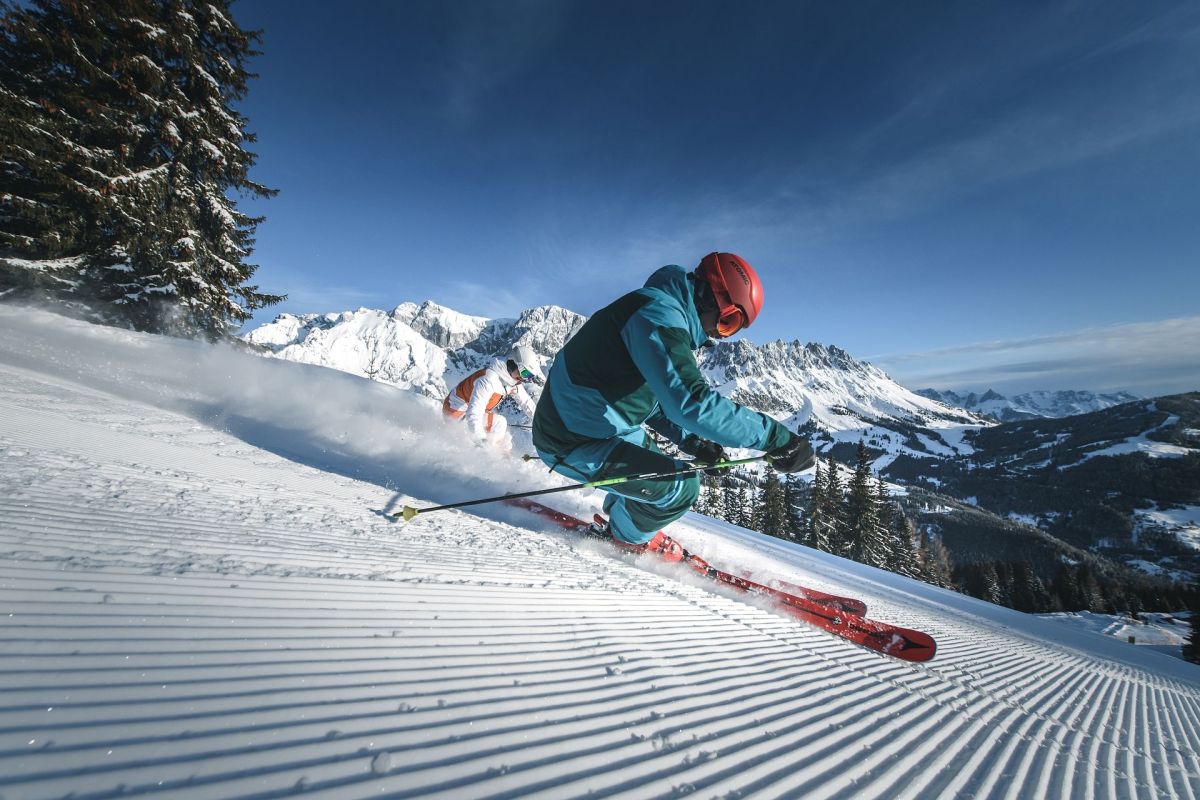 Zwei Skifahrer beim Carven vor dem verschneiten Hochkönigmassiv