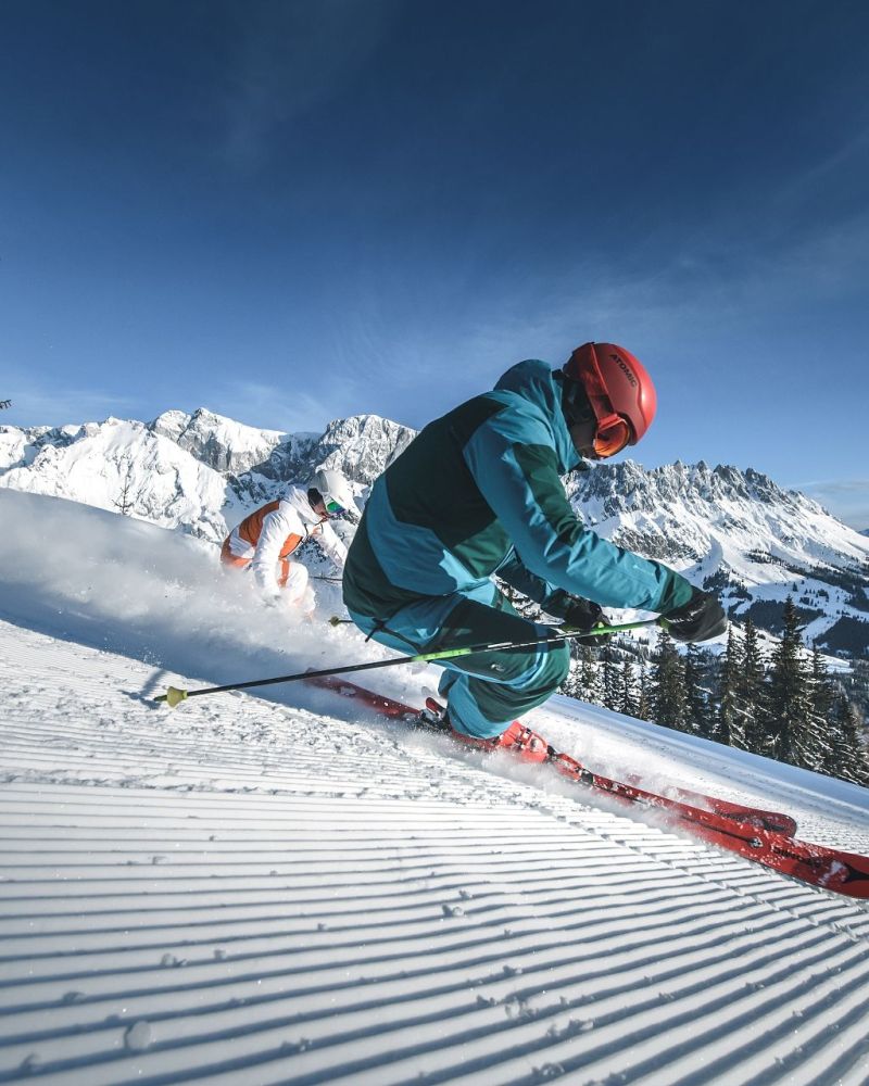Zwei Skifahrer beim Carven vor dem verschneiten Hochkönigmassiv