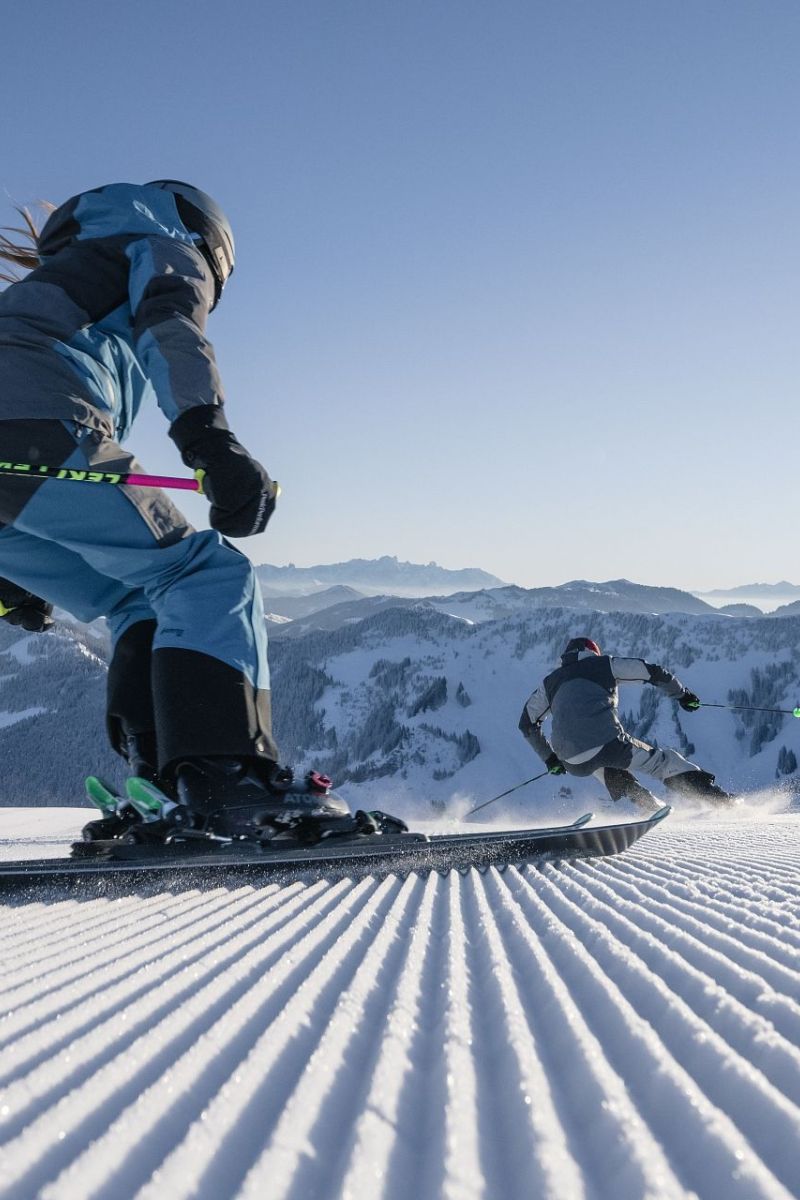 Zwei Skifahrer beim Carven auf frisch präparierter Piste