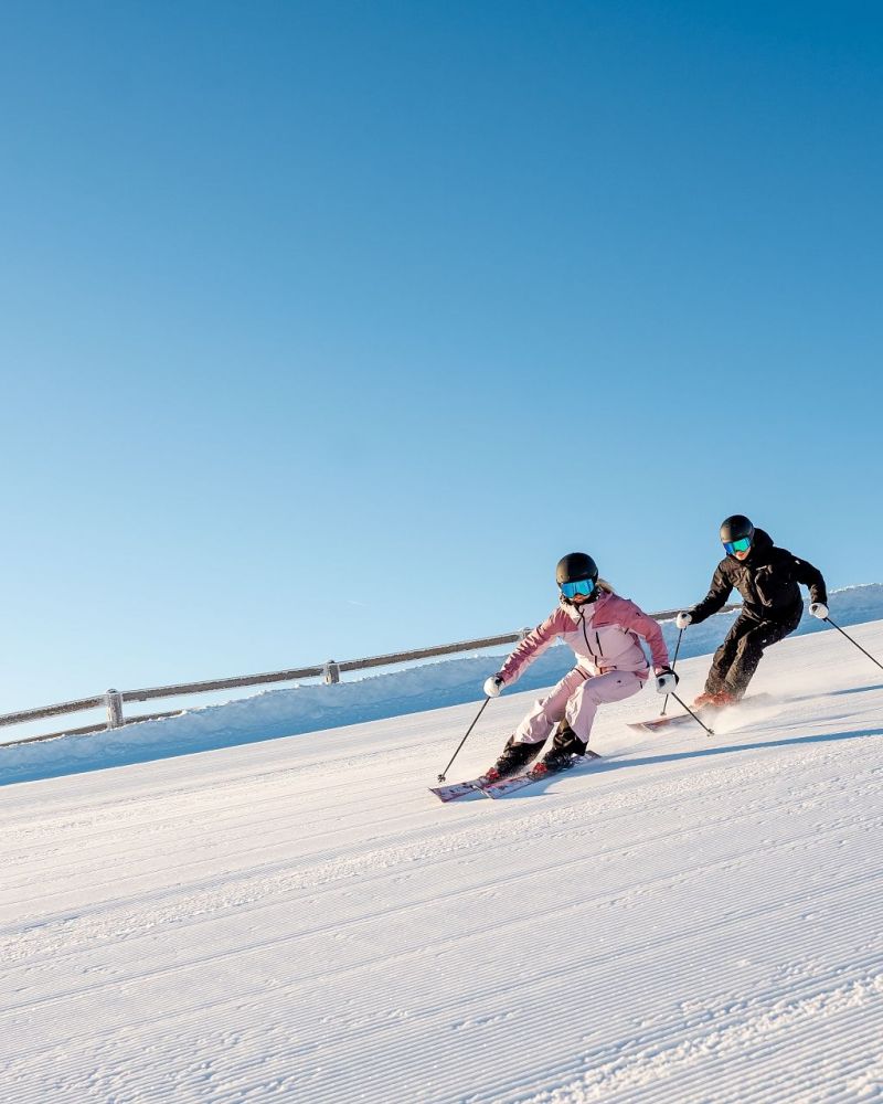 Paar beim Skifahren auf breiter sonniger Piste am Hochkönig