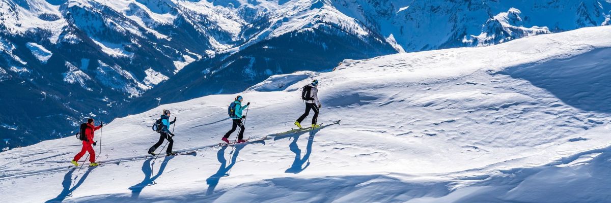 Vier Skitourengeher beim Aufstieg in verschneiter Berglandschaft